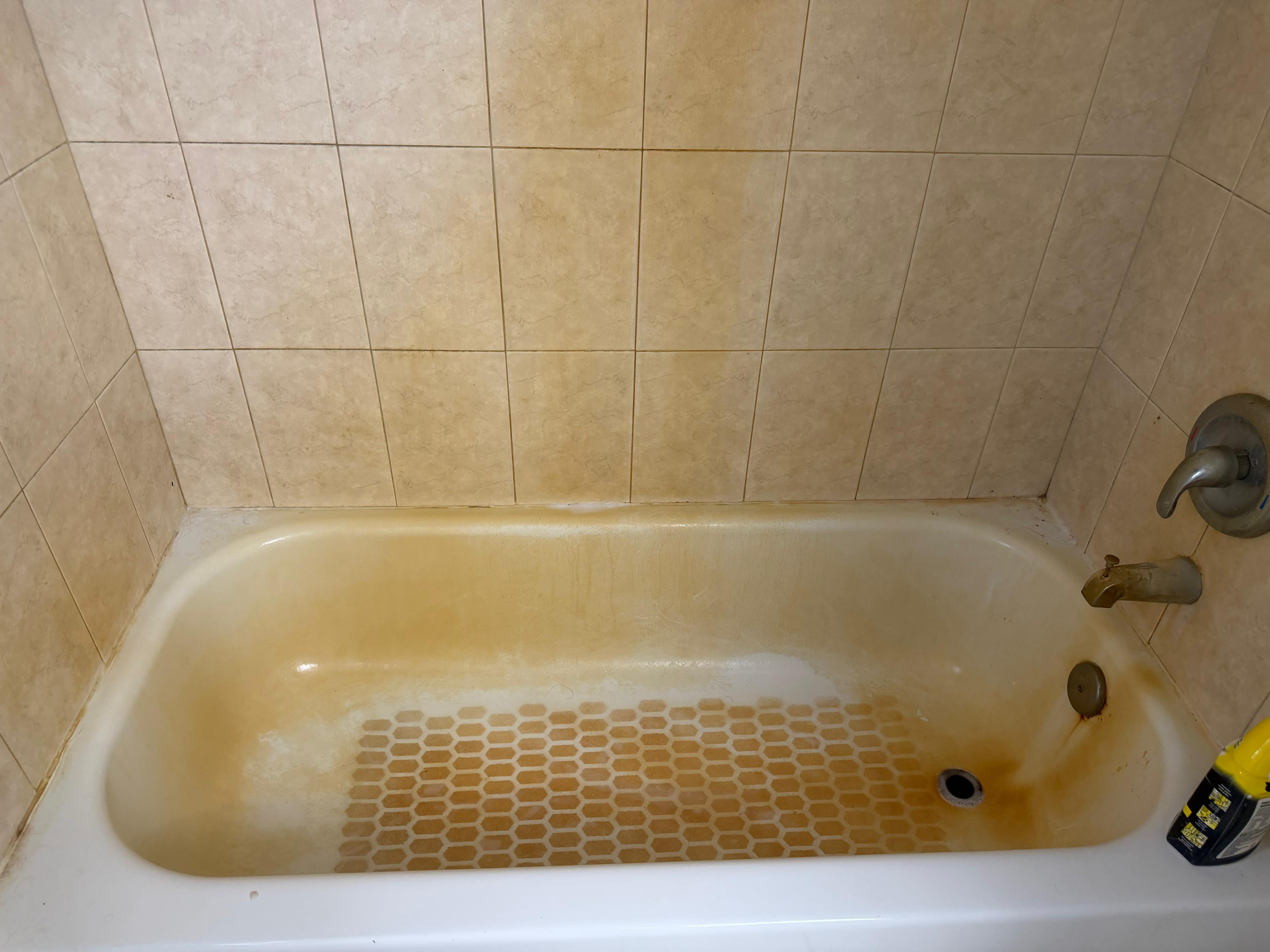 Tampa bathtub with heavy orange hard-water staining before cleaning